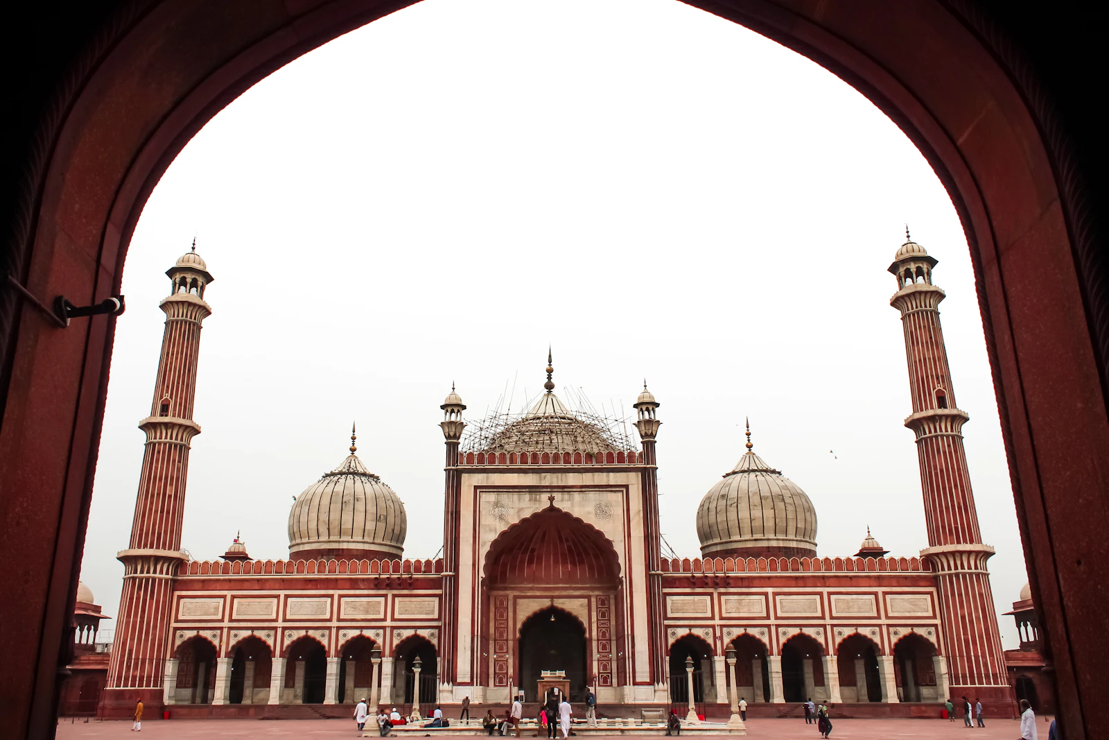 The red sandstone and marble facade of Jama Masjid in Old Delhi, framed by a gateway arch